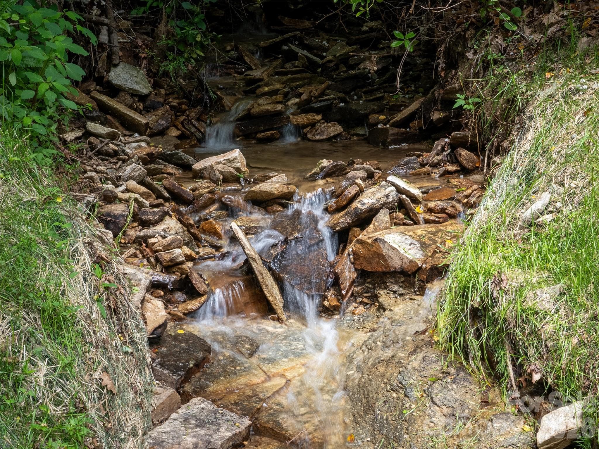 Relax to the Soothing Sounds of Streams as They Coarse Along the Perimeter of the Property. Not one, but TWO Separate Streams Flank the Edges of this Site and Beautifully Converge at the Very Back... - Hendersonville