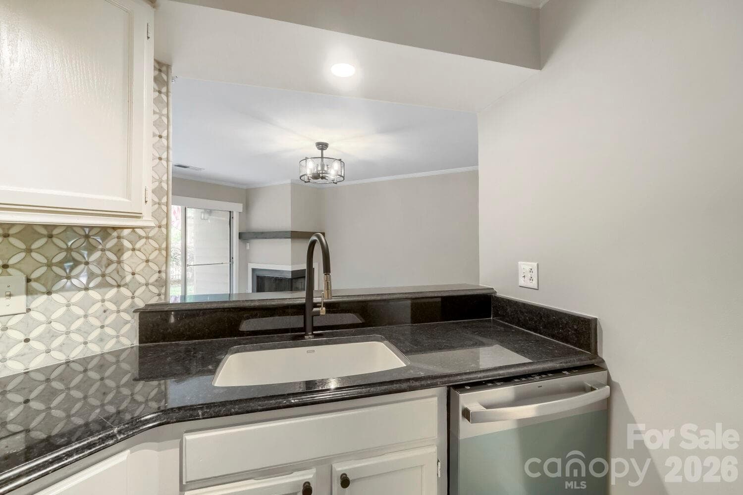 A deep farmhouse-style sink and gooseneck faucet anchor this updated kitchen in timeless style. The view through to the cozy fireside living room makes even dishwashing feel relaxing. - Charlotte