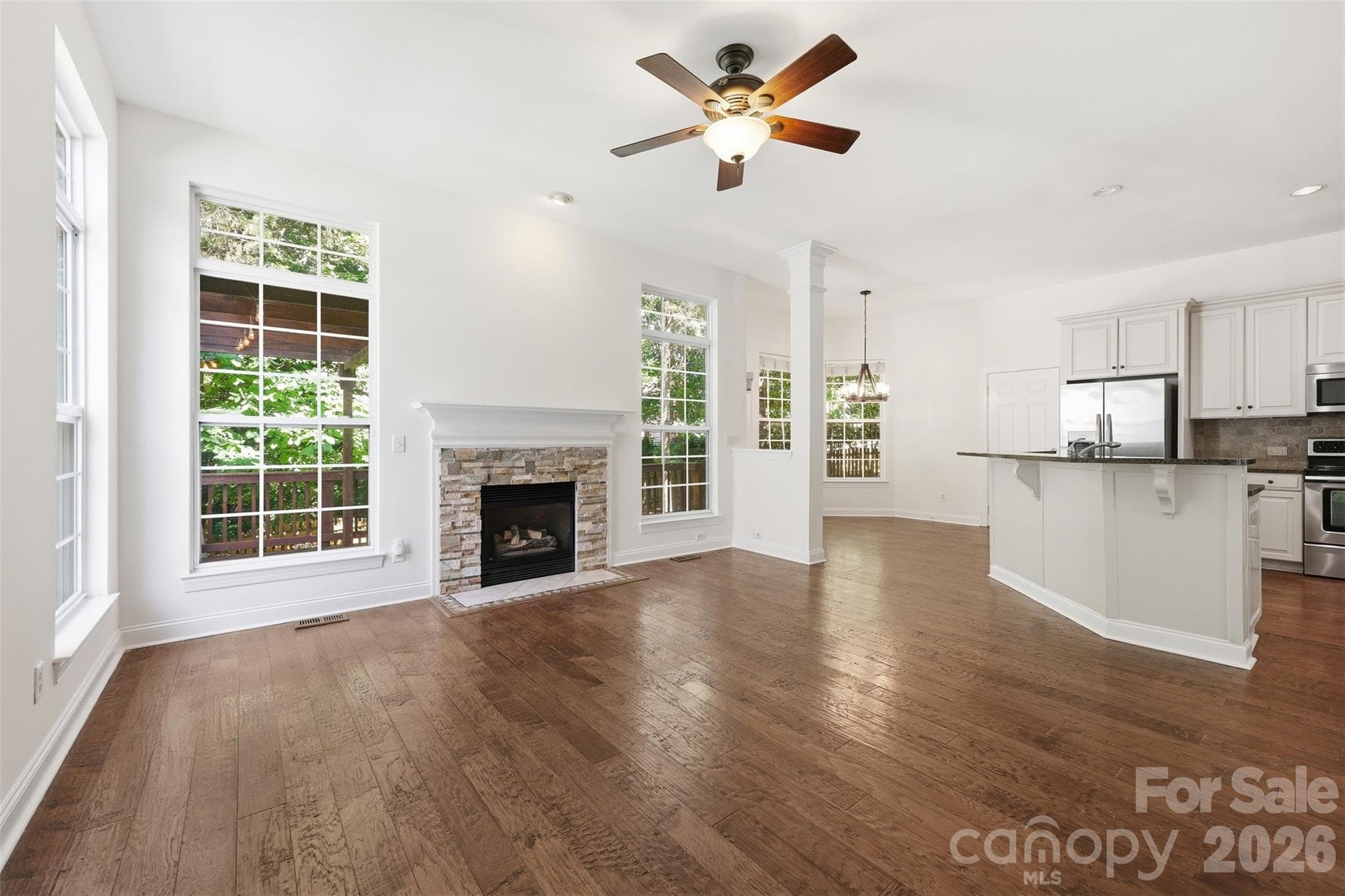 Living Room features a stunning gas fireplace with a stacked stone surround & hand-scraped wide plank hardwood floors - 6832 Charter Hills Road, Charlotte
