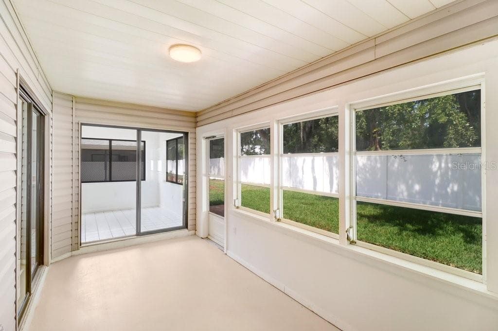 Enclosed porch surrounded by two sliding glass doors in front and to the left.  To the right, a wall of windows and a screen door, is access to rear paver terrace and back yard. - 4949 PLEASANT HOLLOW TRL #211, LAKELAND