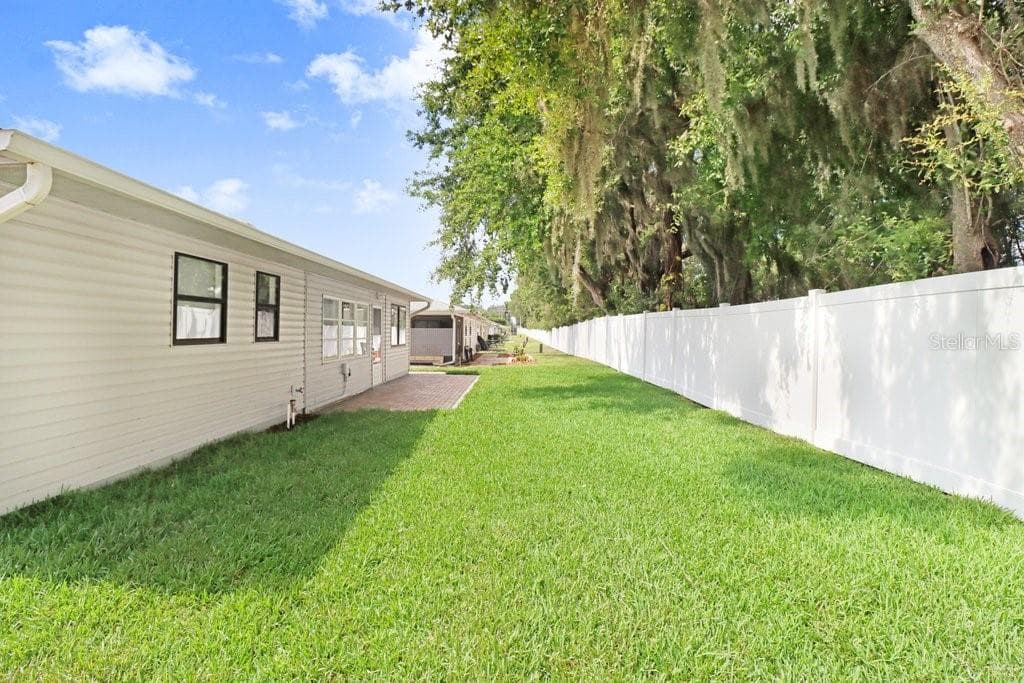 Back yard bordered by rear fence. Neighboring trees provide shade. - 4949 PLEASANT HOLLOW TRL #211, LAKELAND