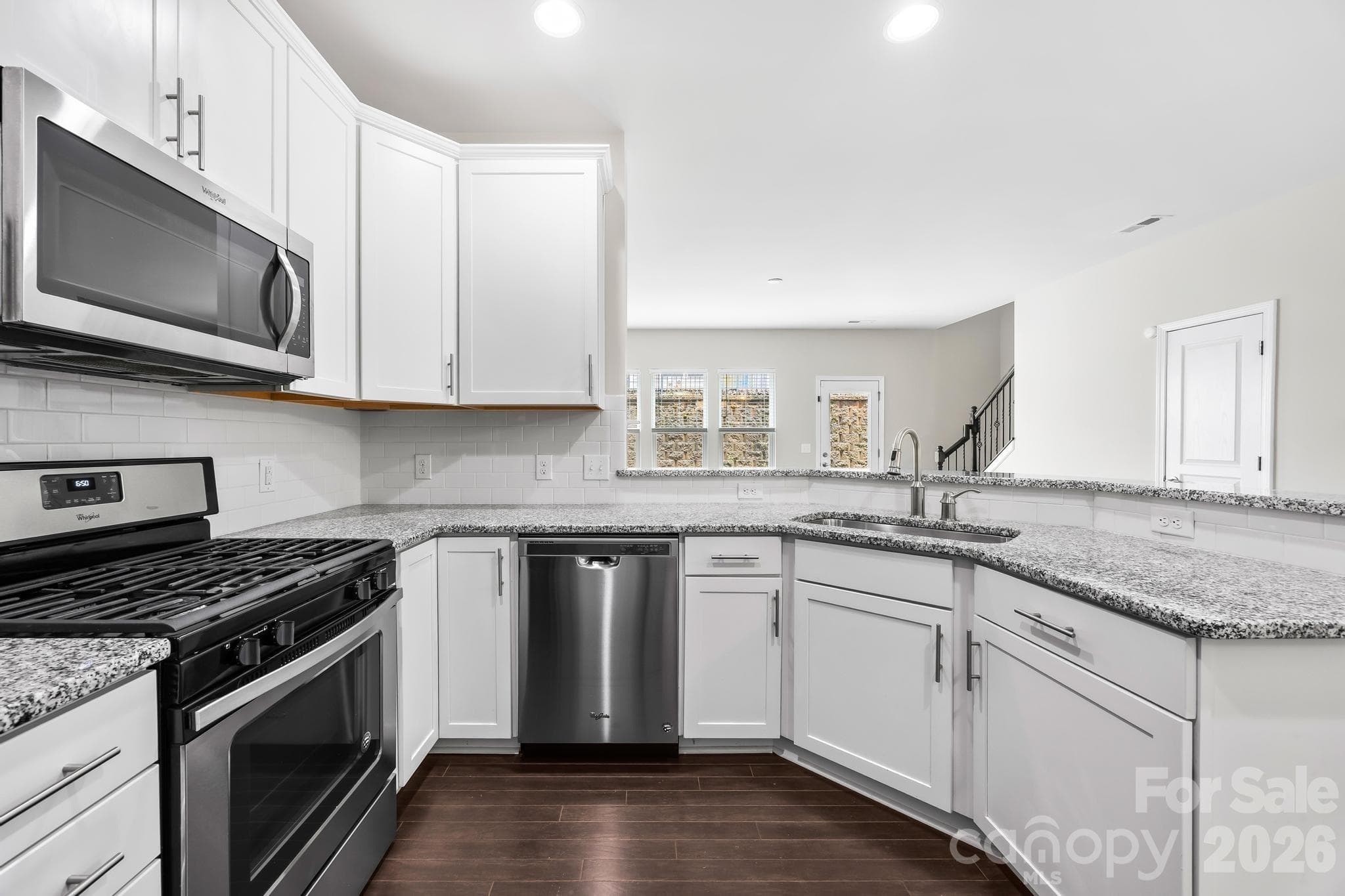 The beautifully appointed kitchen features white cabinetry, granite countertops, a stylish tile backsplash, gas range, and abundant prep space. - Charlotte