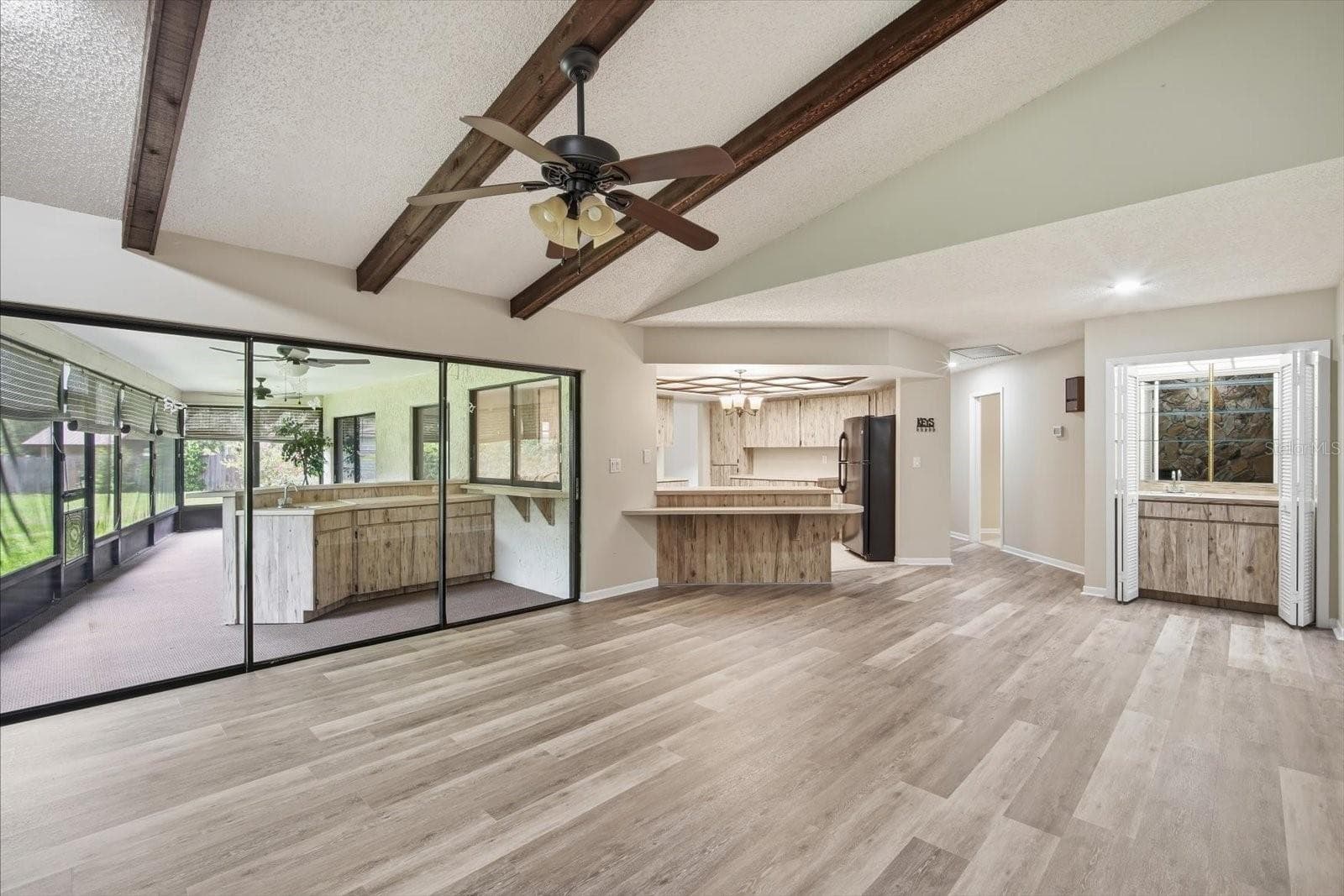 Impressive family room with soaring ceilings with stone fireplace, beams and triple sliding glass doors - 1405 LAUREL CT, PLANT CITY