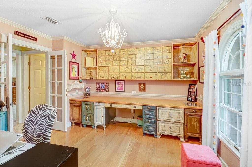 Unique custom cabinetry in home office which is off the front entry and includes hardwood floors and french doors leading to kitchen area. - 1976 DUNLOE CIR, DUNEDIN