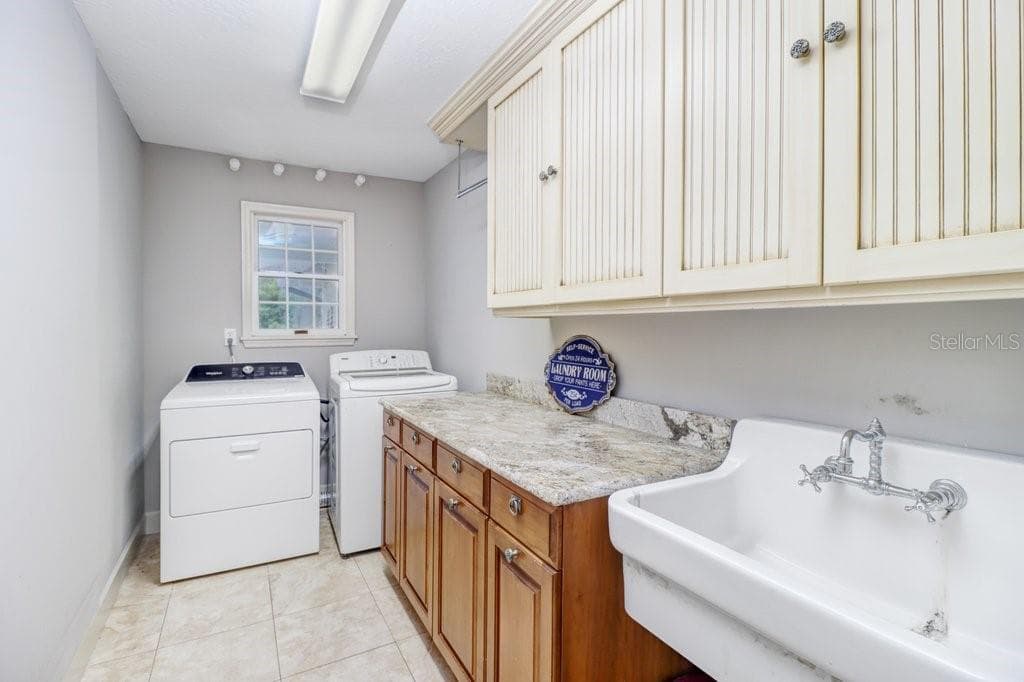 Oversized laundry room with built in custom cabinets, laundry tub, and washer and dryer included. - 1976 DUNLOE CIR, DUNEDIN
