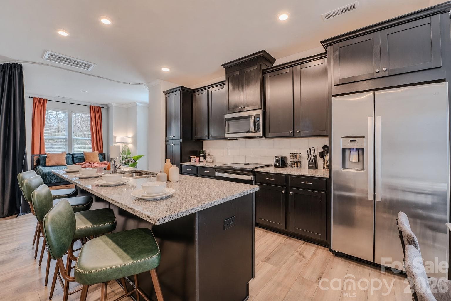 The modern kitchen showcases stainless steel appliances, abundant cabinetry, sleek quartz countertops, a subway tile backsplash, and ample prep space, creating the perfect blend of style and functionality. - 3023 Jolene Court, Charlotte