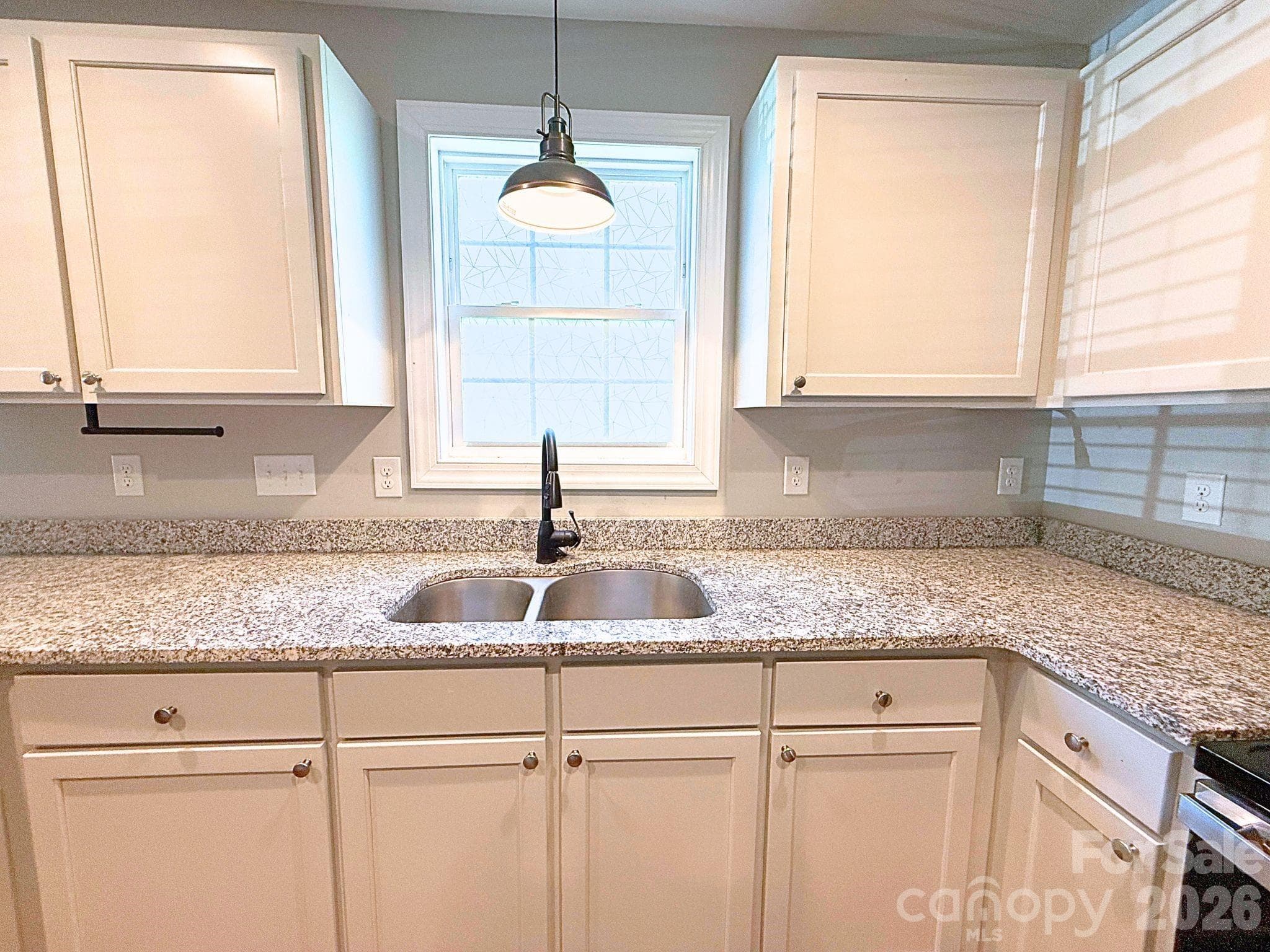 Kitchen – Double-basin sink positioned beneath a window provides natural light while complementing the expansive granite workspace. - Chester