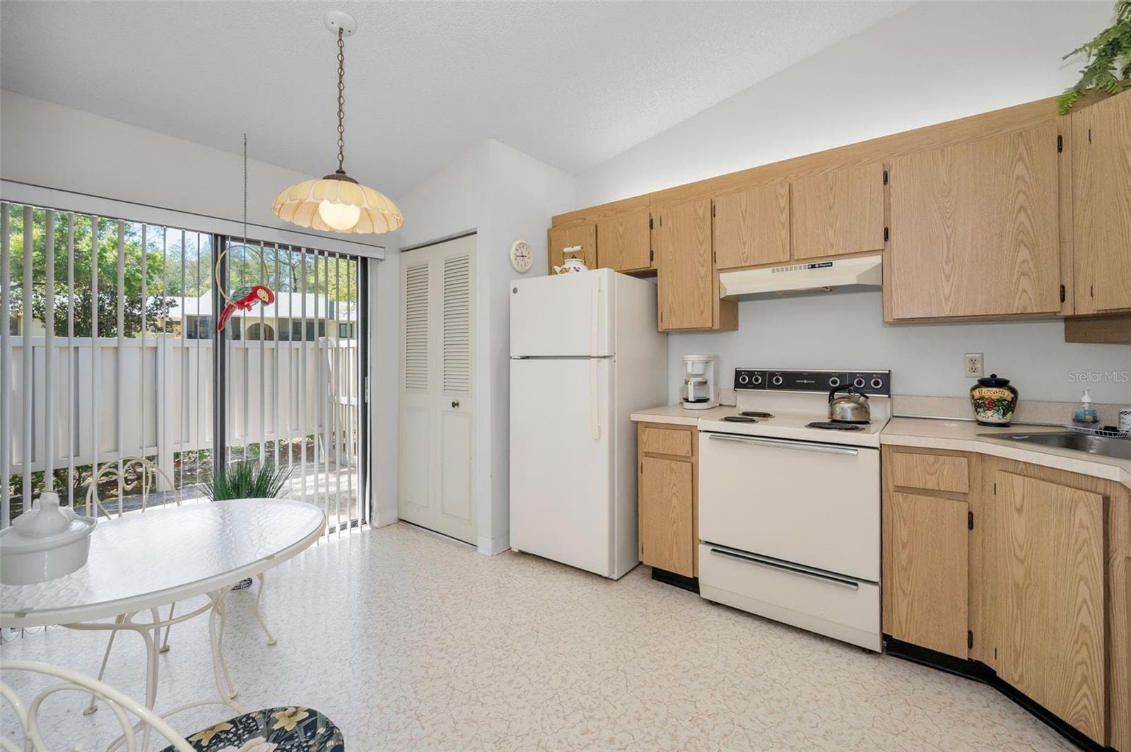 Kitchen With Laundry Closet, Eating Space, and Slider To The Front Patio - 1333 SHADY PINE WAY #F, TARPON SPRINGS