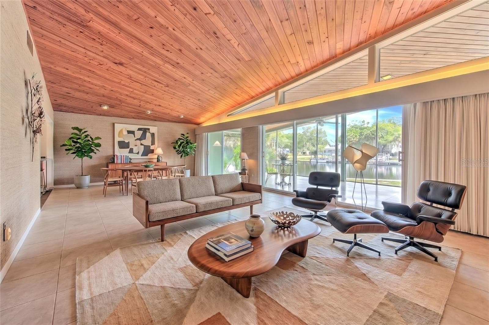virtually staged - Waterfront MCM living room, floor to ceiling glass slider doors, stone fireplace, tongue & groove ceiling - 7102 MANDY LN, NEW PORT RICHEY