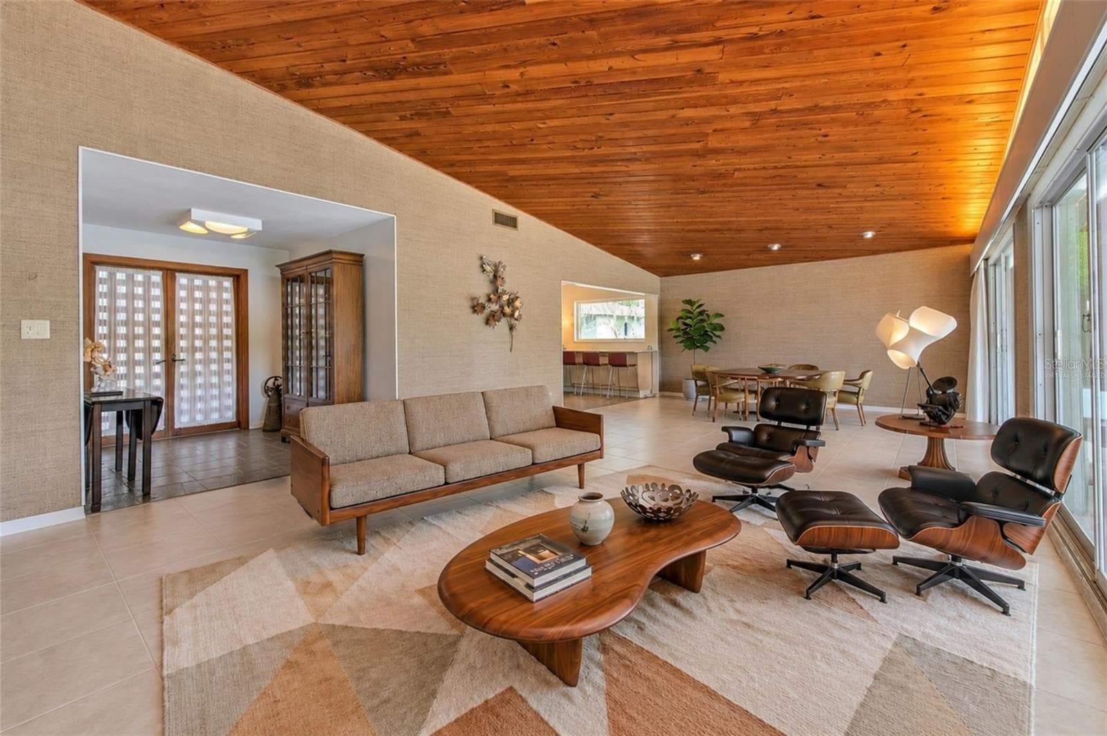 virtually staged -  Waterfront MCM living room, floor to ceiling glass slider doors, stone fireplace, tongue & groove ceiling - 7102 MANDY LN, NEW PORT RICHEY