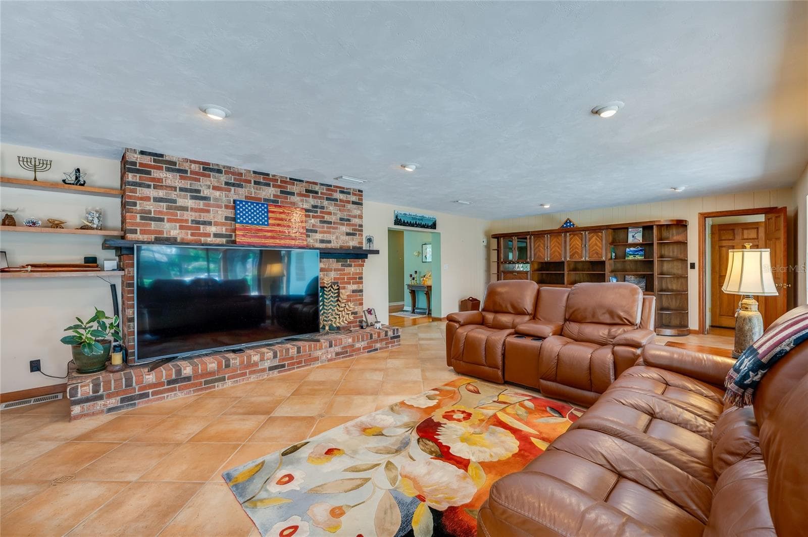 Family room with TV covering part of double-sided fireplace - 697 JOHN ANDERSON DR, ORMOND BEACH