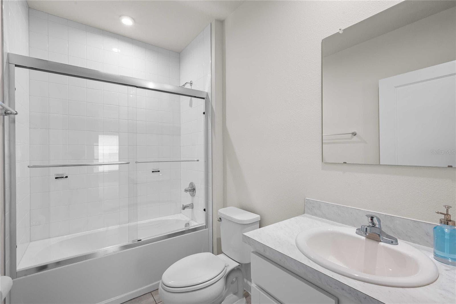 The guest bath has a tub with tile shower surround and a new glass sliding door - 35155 JOMAR AVE, ZEPHYRHILLS