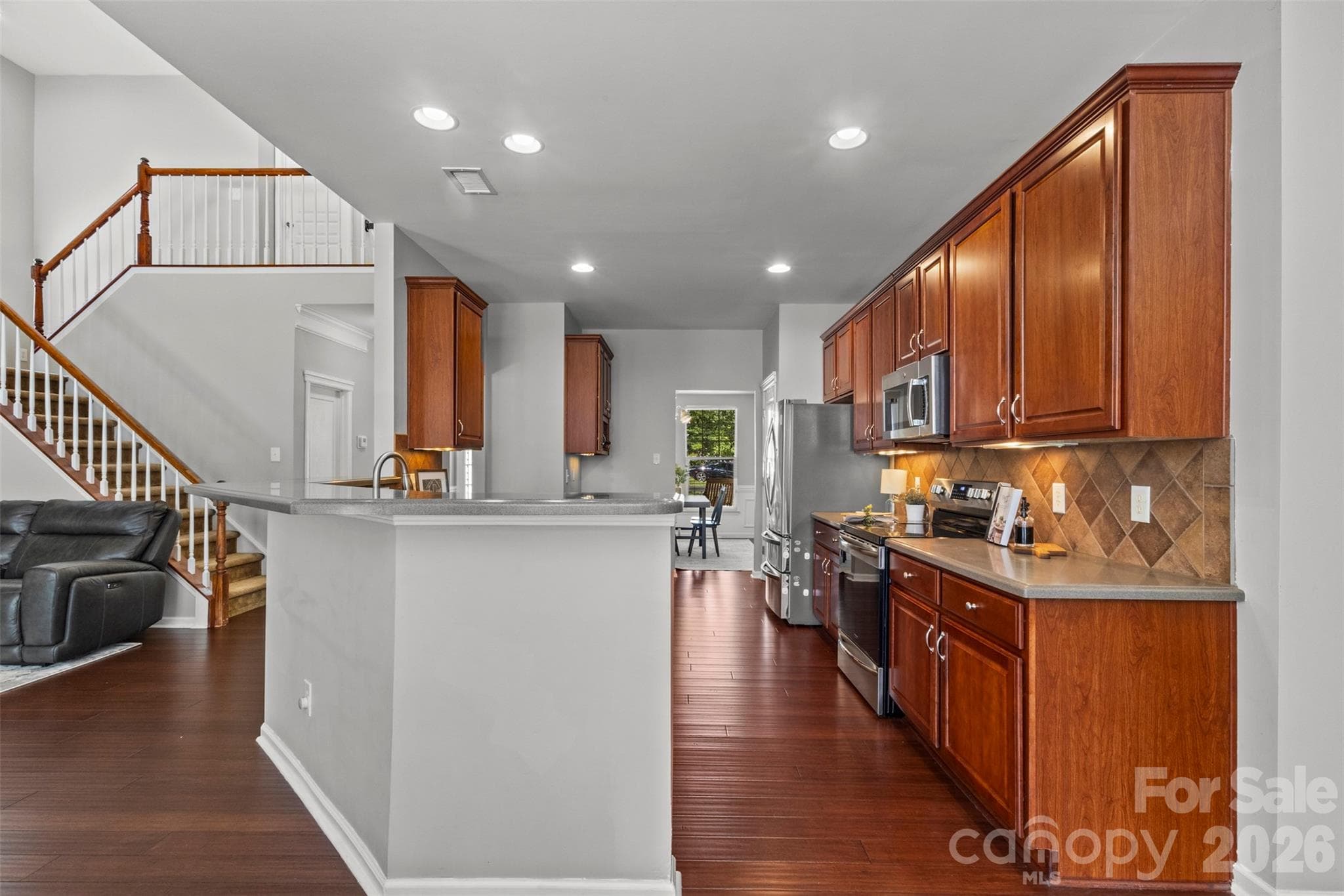 Rich wood cabinetry, a tile backsplash, breakfast bar, and lots on prep space complete this kitchen. - Huntersville