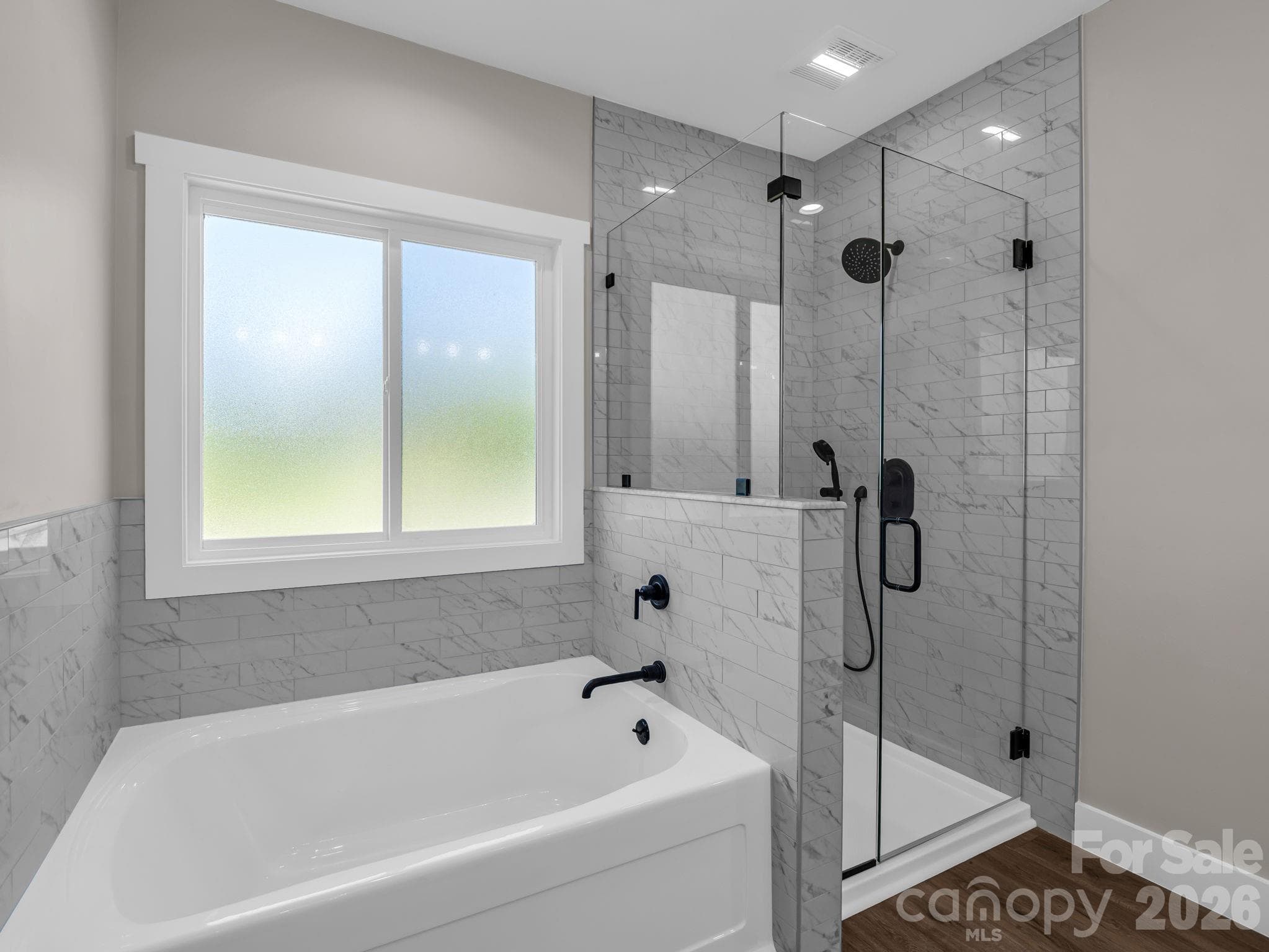 Primary bath offers a beautiful tiled shower and spa like soaking tub.  The windows have privacy glass. - Hendersonville