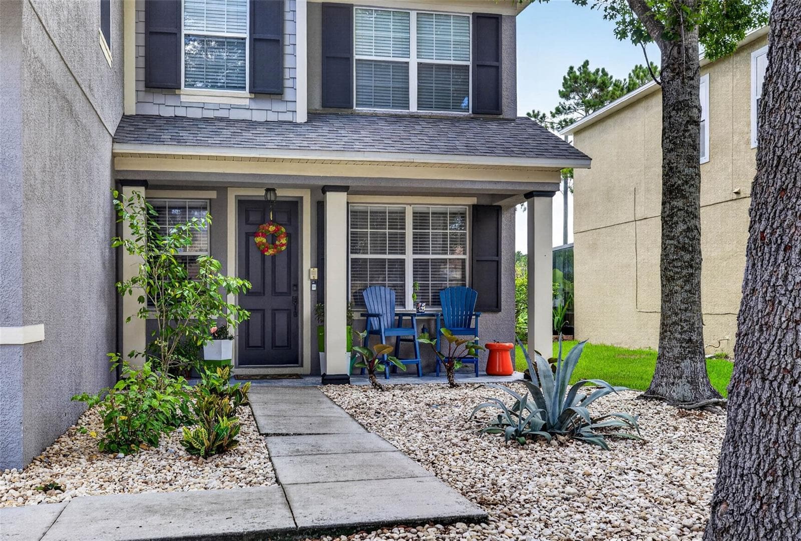 Landscaped front entryway with porch - 7360 BRIDGEVIEW DR, WESLEY CHAPEL