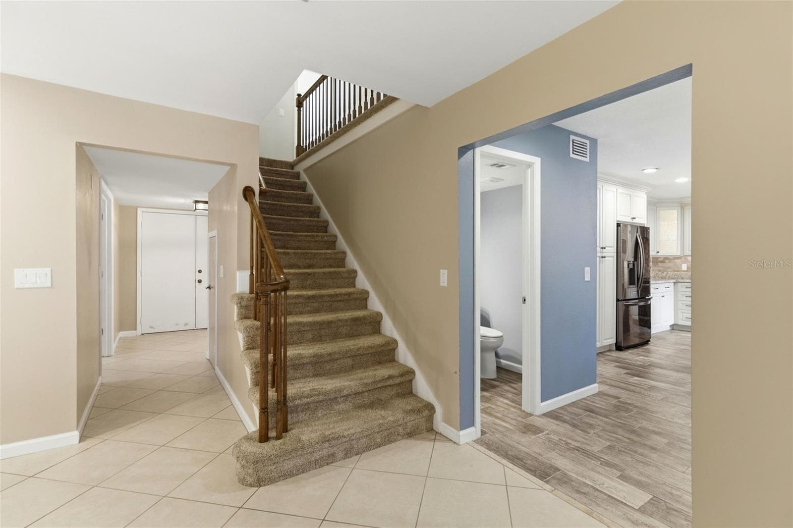 View of entry doors, half bath, kitchen and stairs - 302 BLOOMINGFIELD DR, BRANDON