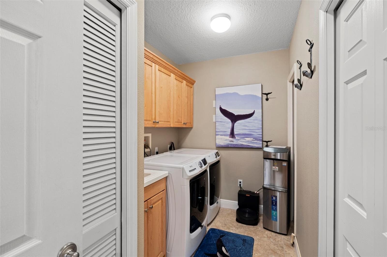 Laundry room off kitchen hallway has a built-in sink and cabinetry for storage , a storage closet and water heater ac , electricity box room. - 17717 GULF BLVD #604, REDINGTON SHORES