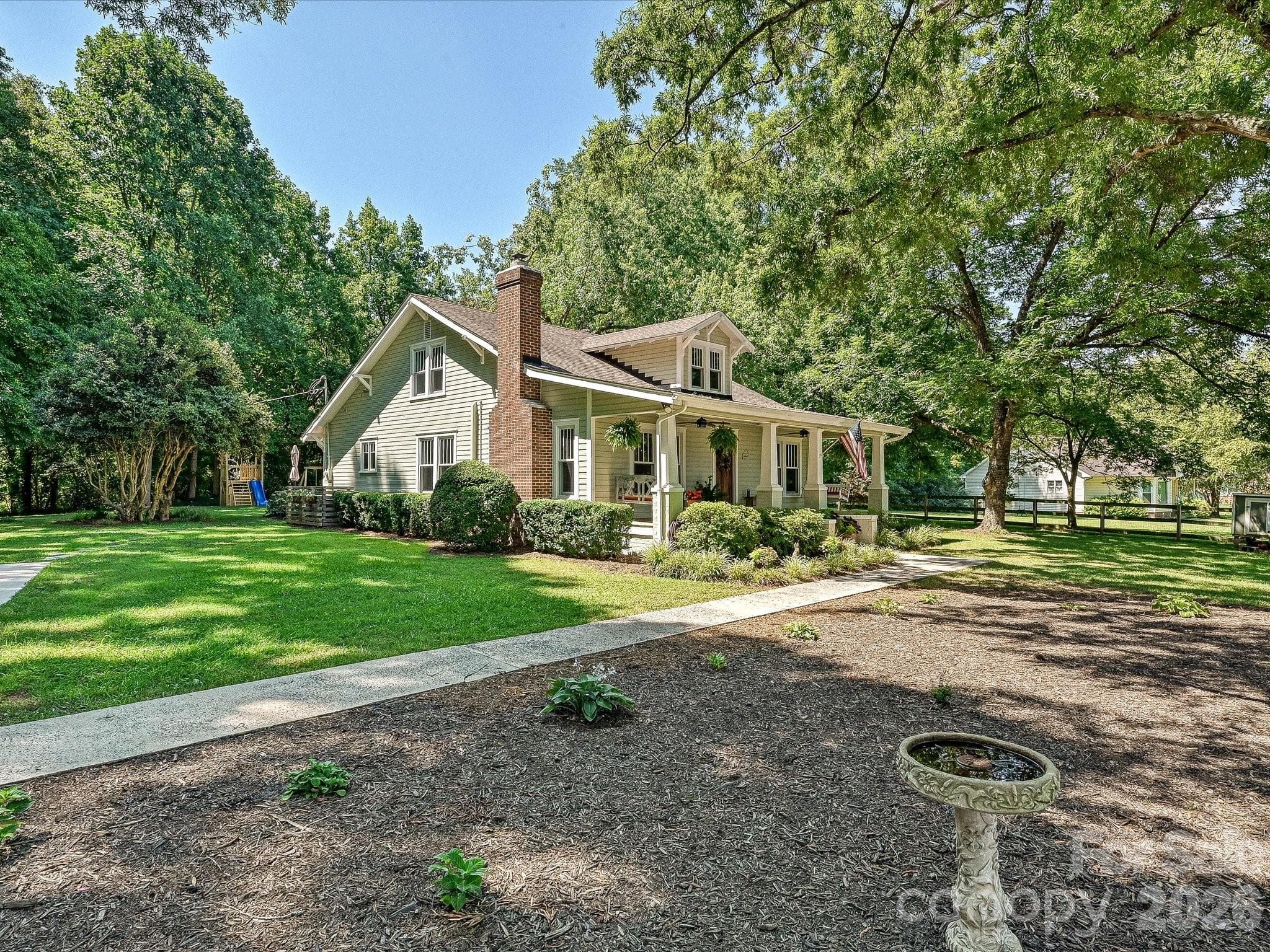 Classic Southern charm meets timeless curb appeal with a welcoming wraparound porch, mature shade trees, and a beautifully landscaped homesite. - 3514 Kelly Road, Charlotte