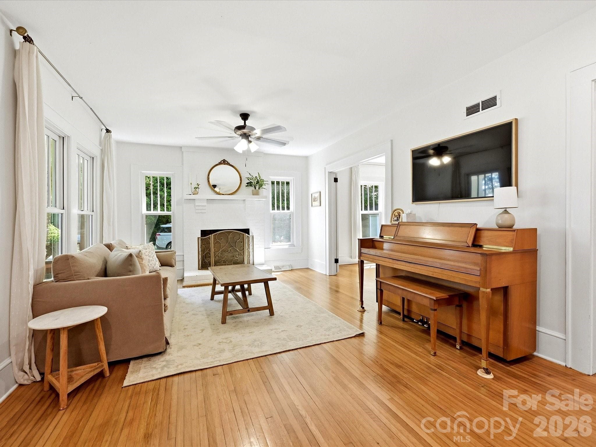 Bright and inviting living spaces feature classic hardwood floors, oversized windows, and a cozy fireplace that serves as the heart of the home. - 3514 Kelly Road, Charlotte