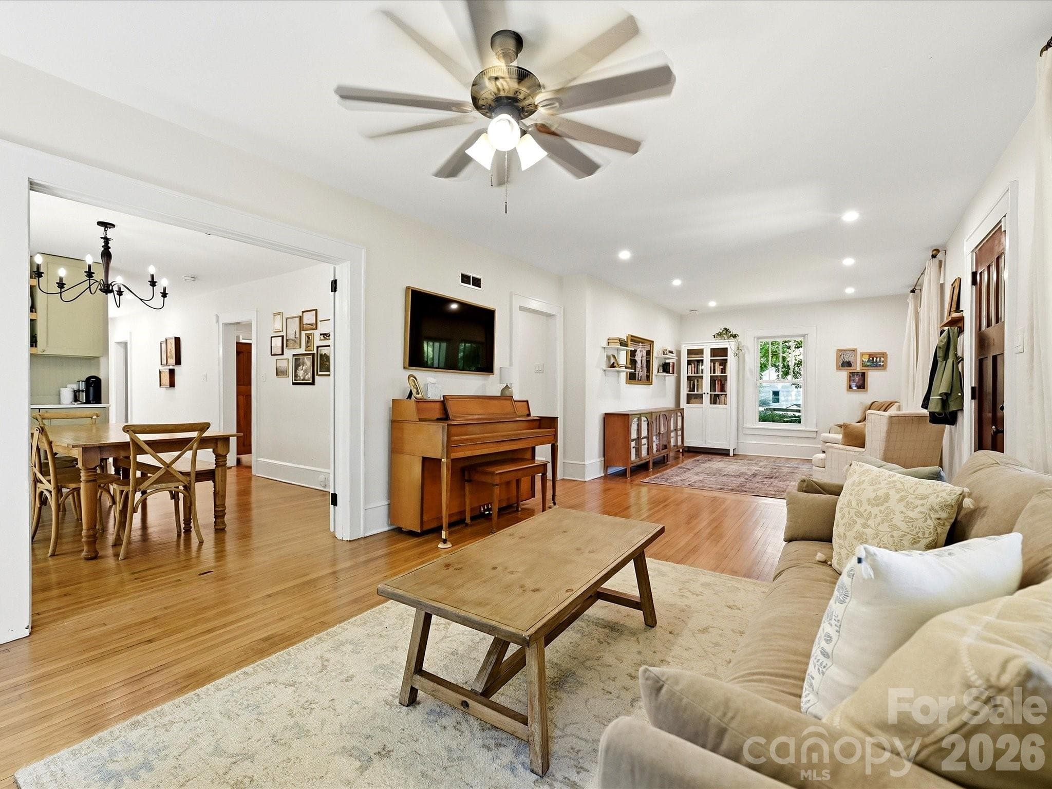 Enjoy an open, light-filled living area with charming architectural details, gleaming hardwood floors, and views of the welcoming front porch. - 3514 Kelly Road, Charlotte