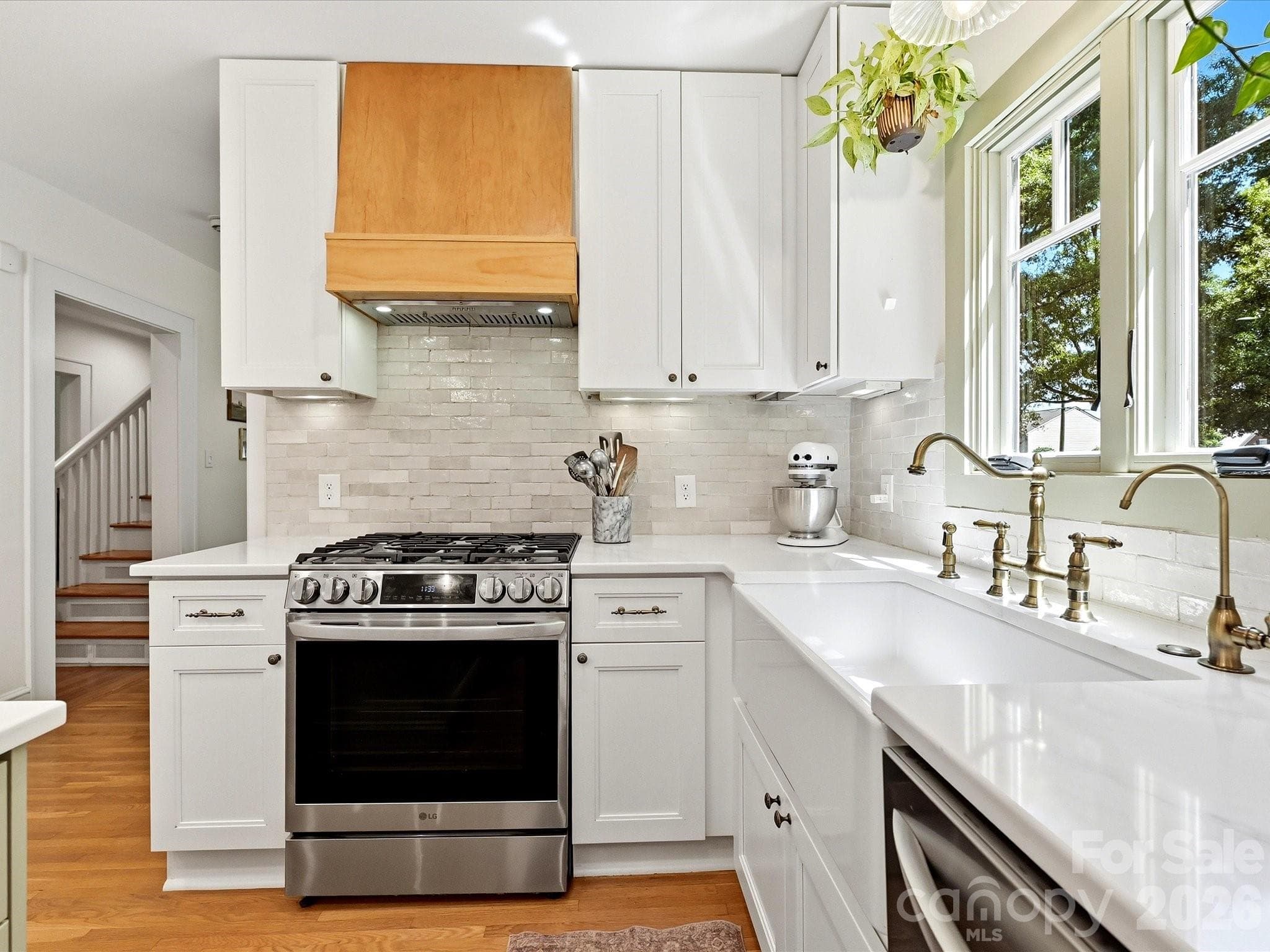 The beautifully updated kitchen features quartz countertops, a farmhouse sink, stainless steel appliances, a center island with seating, and direct access to the outdoor living space. - 3514 Kelly Road, Charlotte