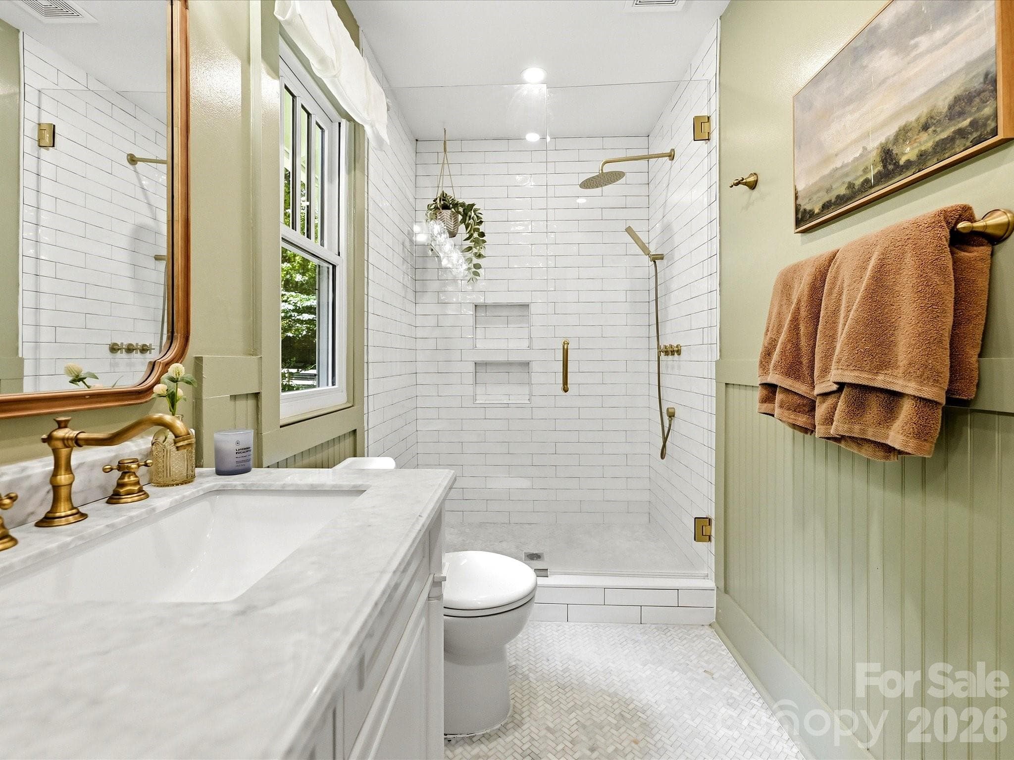 Beautifully renovated, this spa-inspired bathroom features a marble-topped dual vanity, designer fixtures, and a stunning walk-in tiled shower with frameless glass enclosure. - 3514 Kelly Road, Charlotte