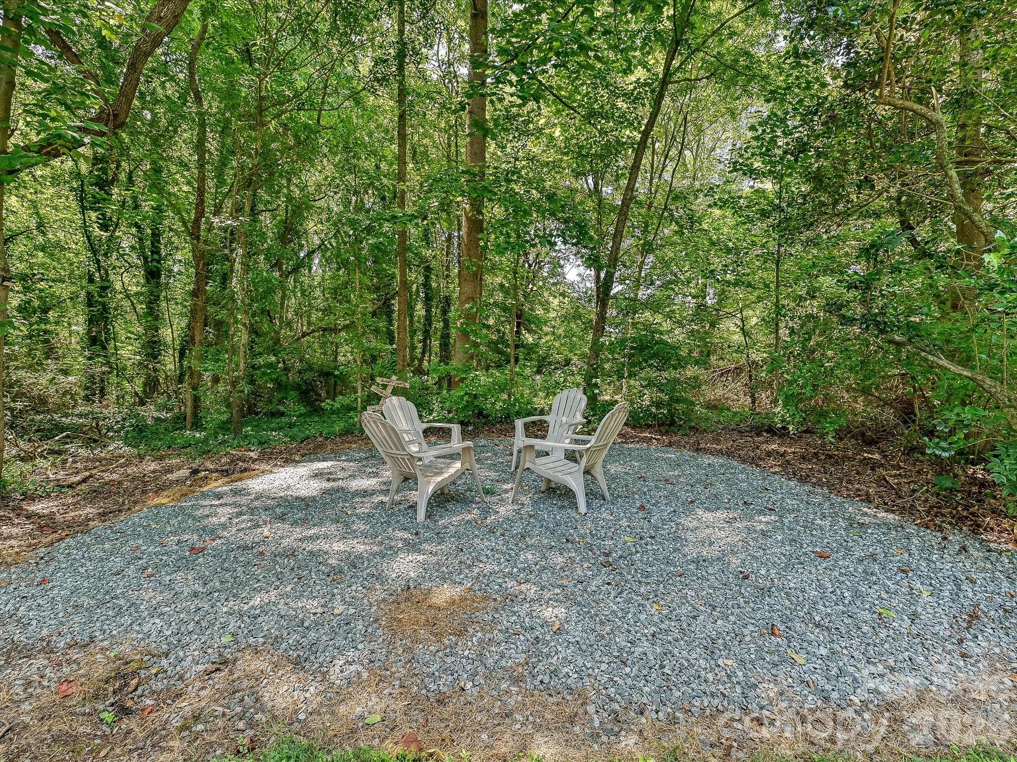 Gather around the private fire area perfect for a fire pit, nestled among mature trees and great for cozy evenings under the stars. - 3514 Kelly Road, Charlotte