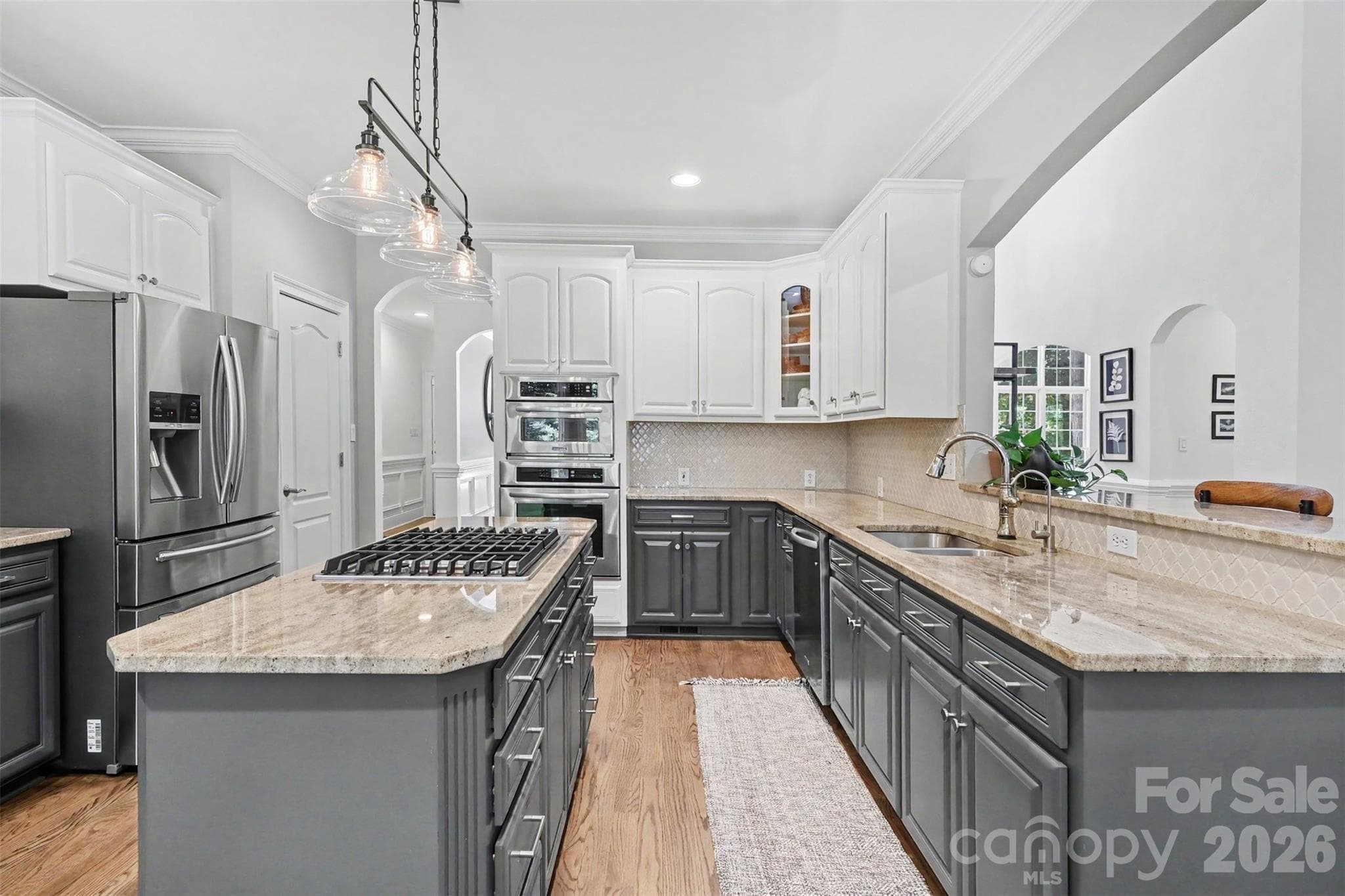 Refreshed designer kitchen featuring two-tone cabinetry, granite countertops, tile backsplash, center island with gas cook top, wall ovens, pantry, and under-sink water filtration. - 109 Whiterock Drive, Mount Holly