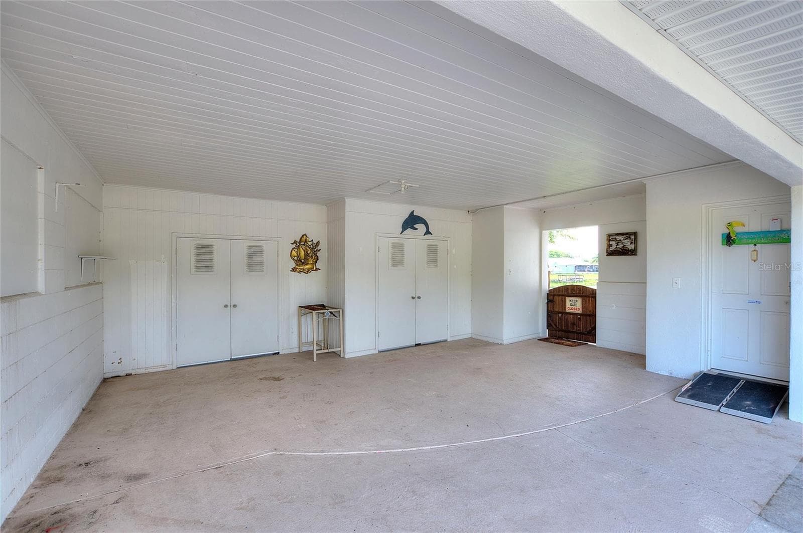 Enclosed carport/garage area. The doors in the back are to storage areas. - 6197 AMARYLLIS DR, INDIAN LAKE ESTATES