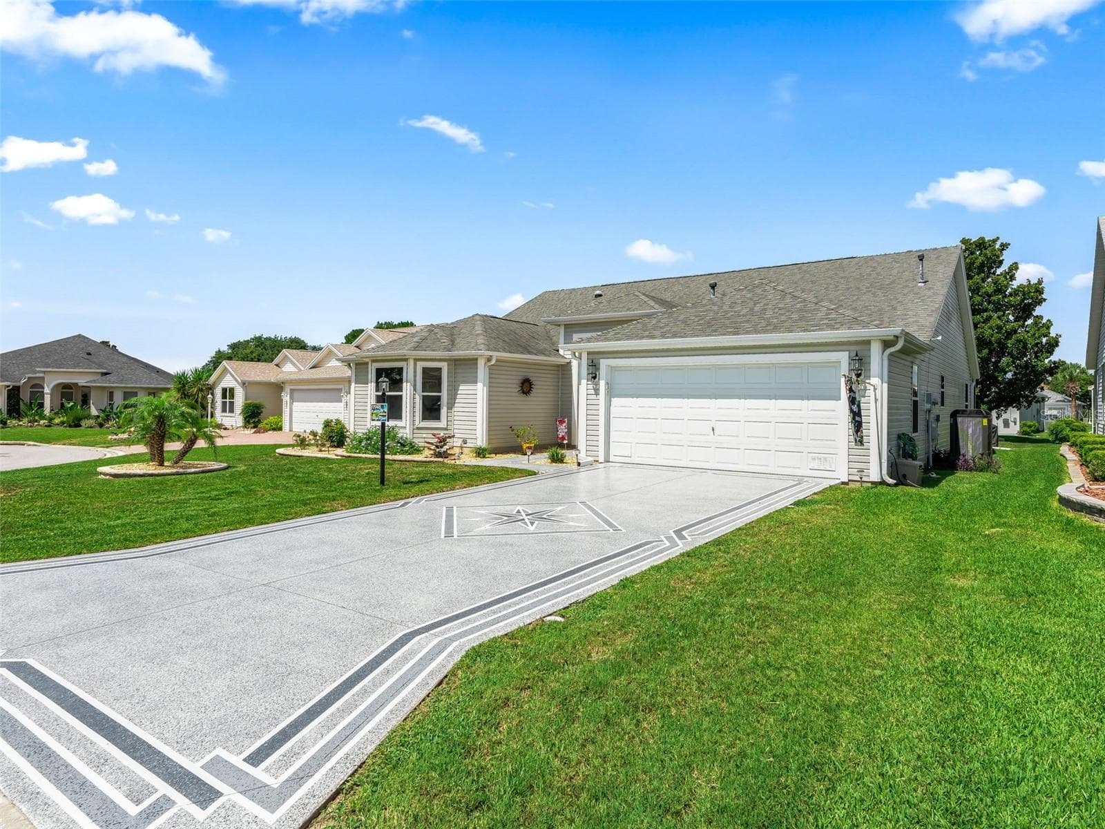 Wide custom painted driveway, manicured lawn, and attractive side elevation enhance the home’s curb appeal and provide a spacious, open feel. - 17946 SE 87TH MELROSE CT, THE VILLAGES