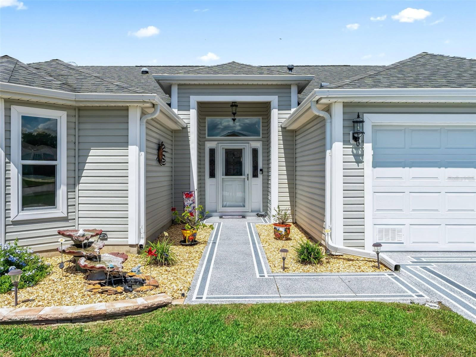 Welcoming covered entry with glass-accented front door, sidelights, and a decorative walkway offers a polished first impression. - 17946 SE 87TH MELROSE CT, THE VILLAGES