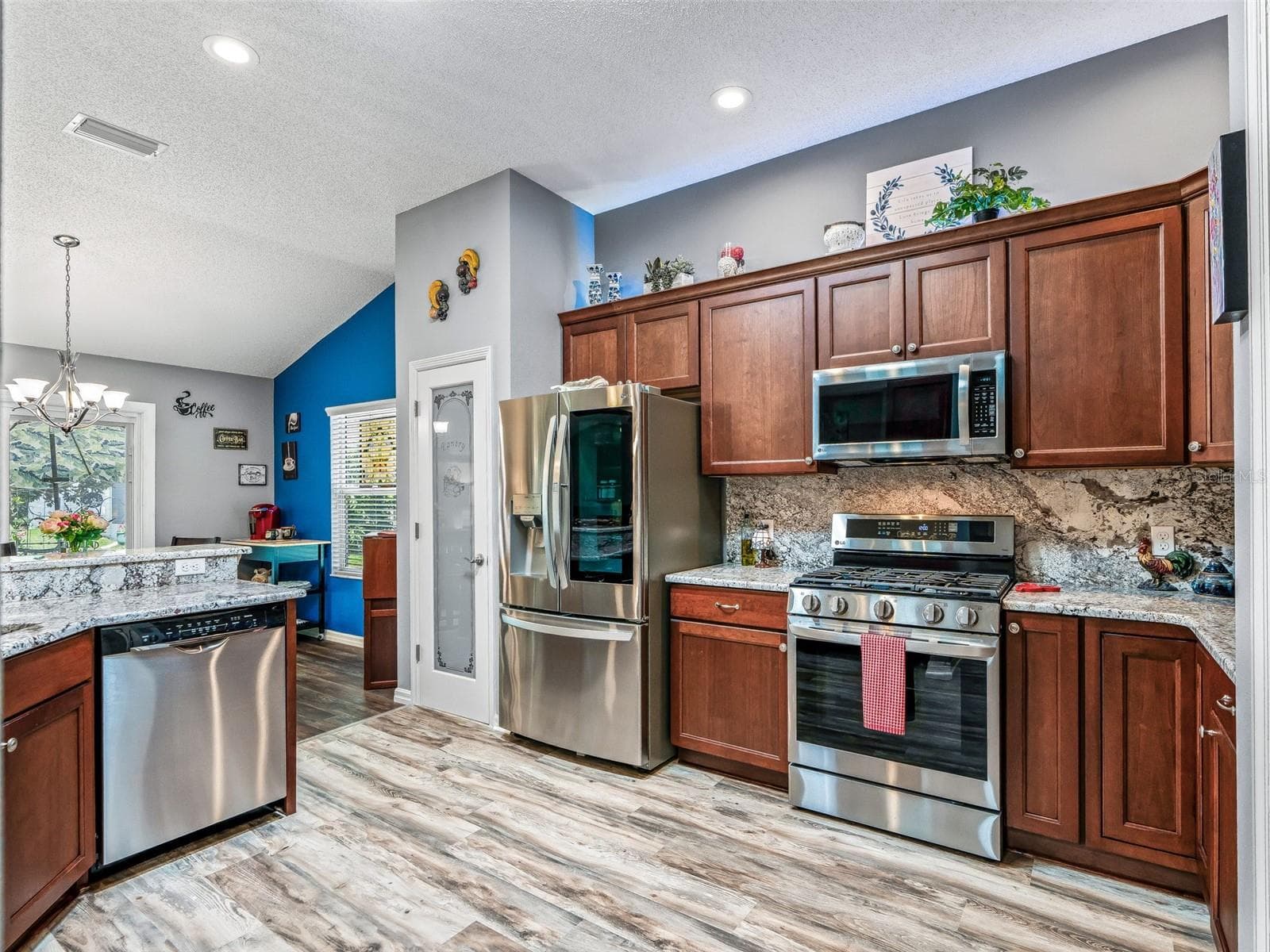 Warm wood cabinetry, stainless steel appliances, granite countertops, tile backsplash, and durable flooring combine for an attractive and practical kitchen. - 17946 SE 87TH MELROSE CT, THE VILLAGES