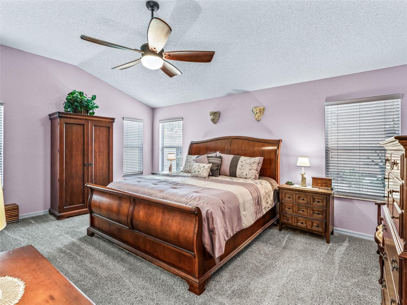 Generously sized primary suite features soft carpeting, multiple windows, a ceiling fan, and ample space for a complete bedroom furniture arrangement. - 17946 SE 87TH MELROSE CT, THE VILLAGES