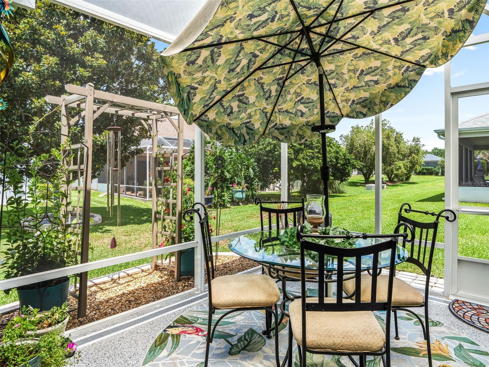 A charming patio beneath a decorative canopy umbrella offers a comfortable setting for outdoor dining, morning coffee, or casual entertaining. Birdcage is roofed with clear Florida plexiglass for a dry environment! - 17946 SE 87TH MELROSE CT, THE VILLAGES