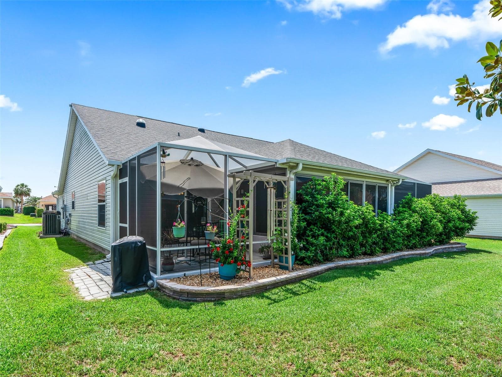 A screened lanai, shaded patio, and attractive garden borders extend the home’s living space into the outdoors. - 17946 SE 87TH MELROSE CT, THE VILLAGES