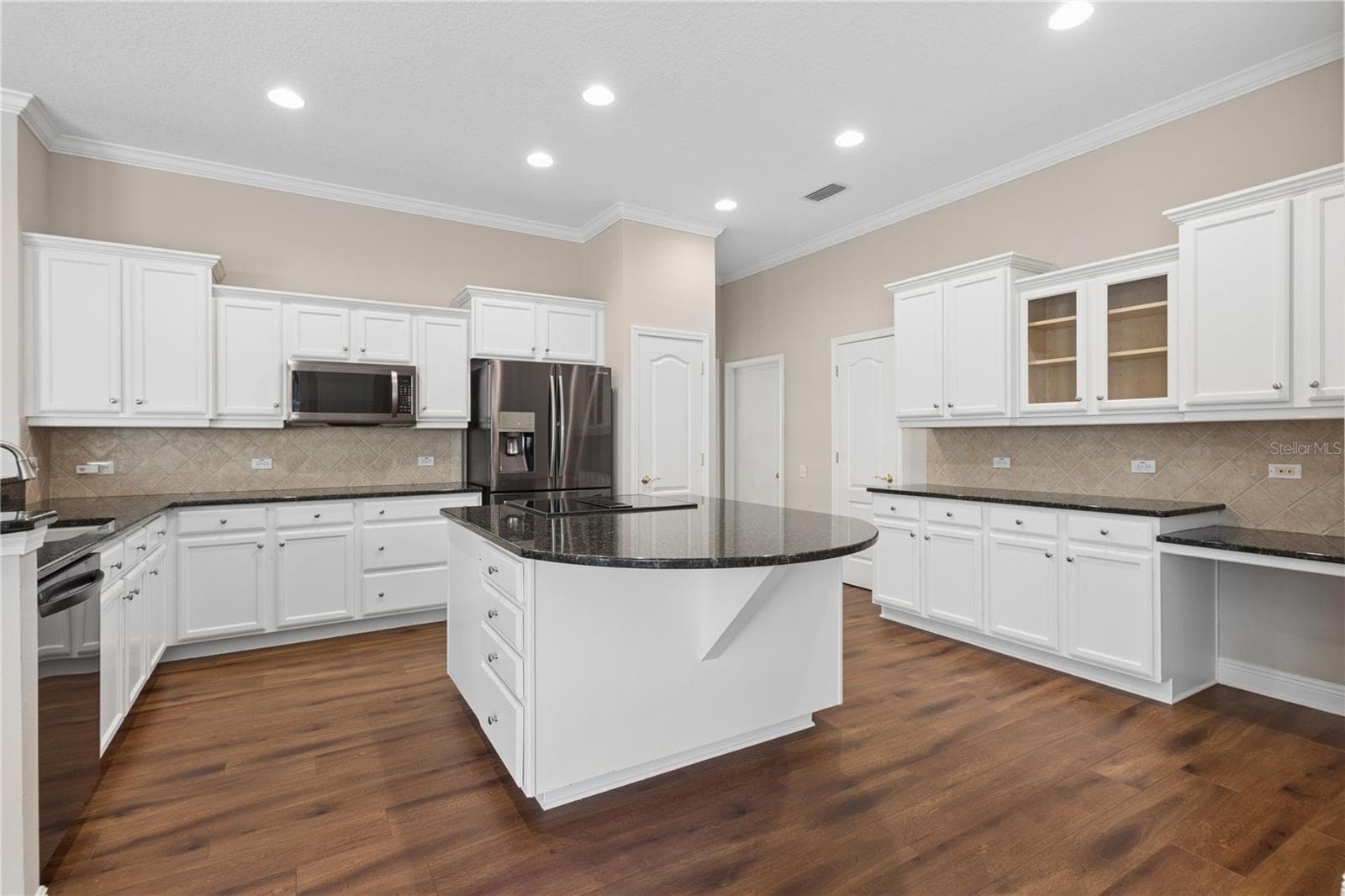 The heart of the home, the open kitchen features generous counter space, abundant cabinetry, a built-in desk, and relaxing views of the pool. - 26920 WINGED ELM DR, WESLEY CHAPEL