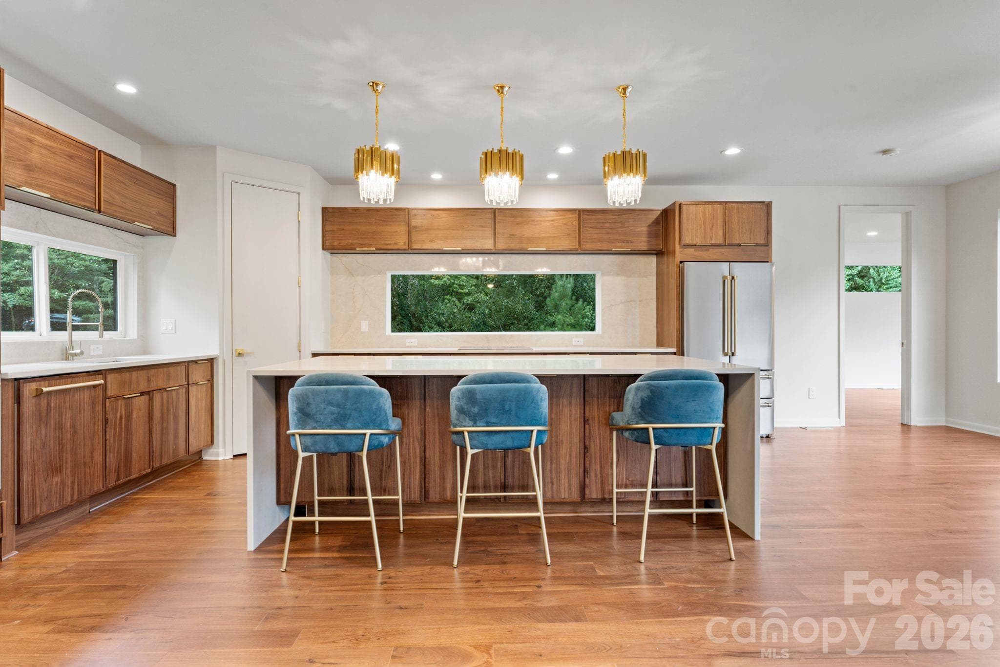 Modern chef's kitchen with waterfall quartz island, custom oak cabinetry, and pro-grade stainless appliances - 1064 Greylyn Drive, Matthews