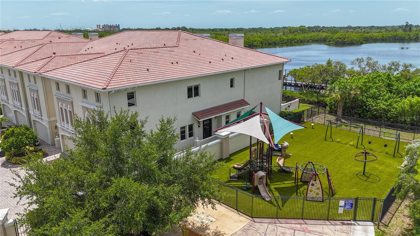 Sideyard showing the playground next to this end unit, and the waters of Weedon Island Preserve in the background. - 1008 PASEO DEL RIO NE, ST PETERSBURG