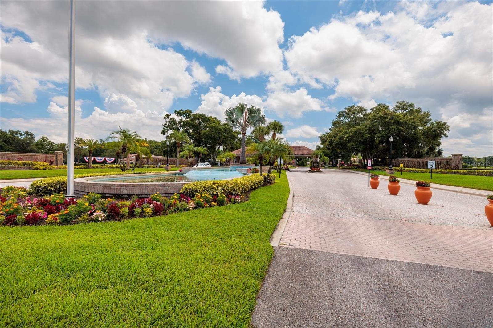 Entering Crescent Oaks, greeting by beautiful landscaping and the guarded entry - 1338 DARTFORD DR, TARPON SPRINGS