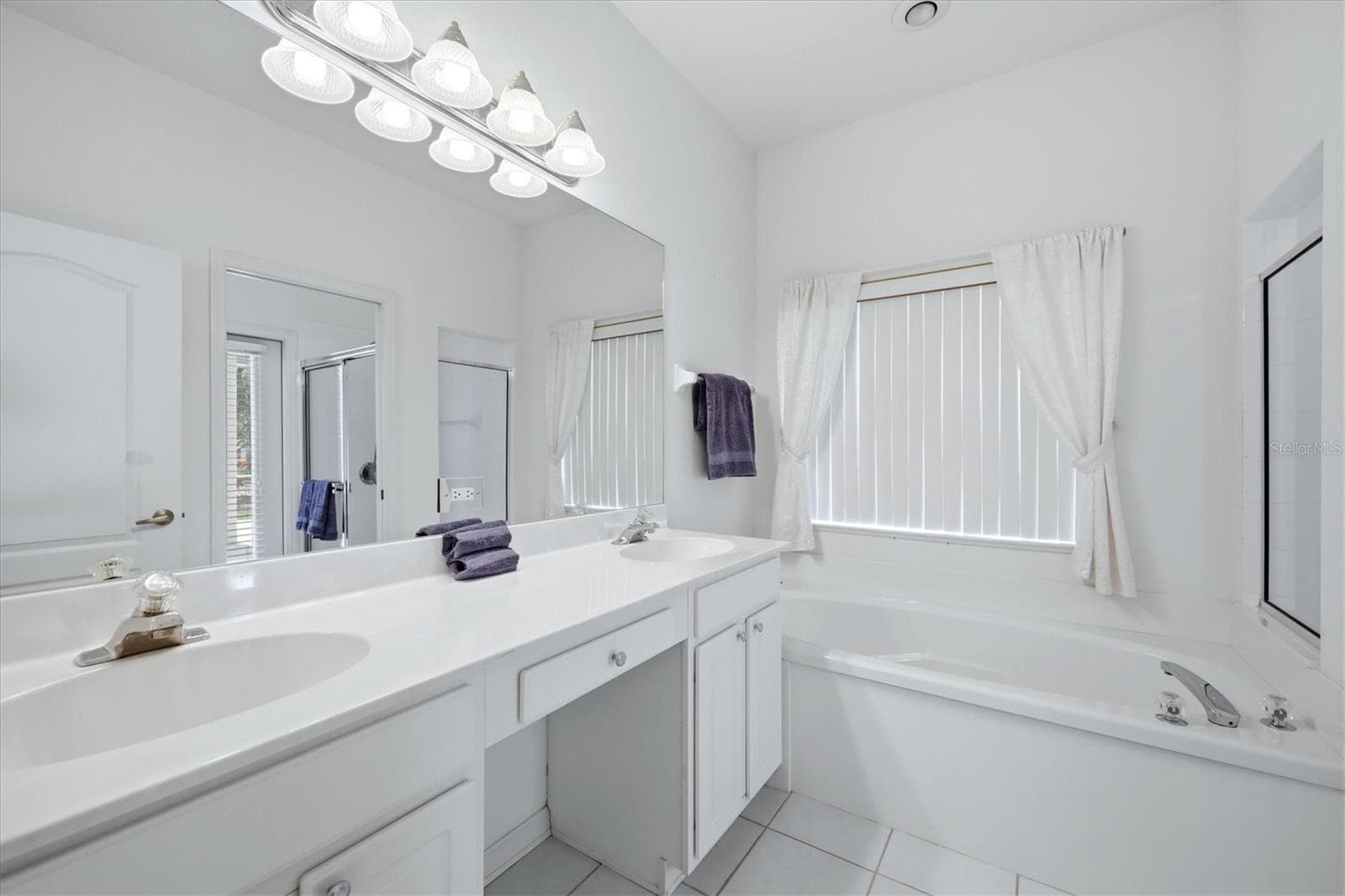 bathroom with double vanity, white cabinetry, large mirror and modern finishes - 8492 IDLEWOOD CT, LAKEWOOD RANCH