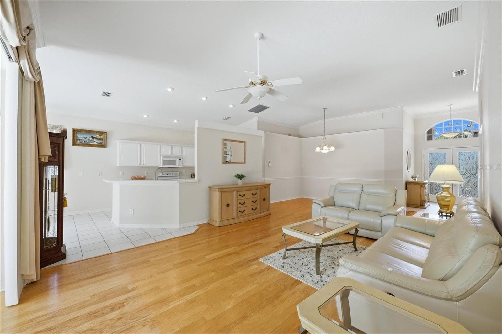 Spacious living area with hardwood floors, kitchen island and views toward screened lanai - 8492 IDLEWOOD CT, LAKEWOOD RANCH