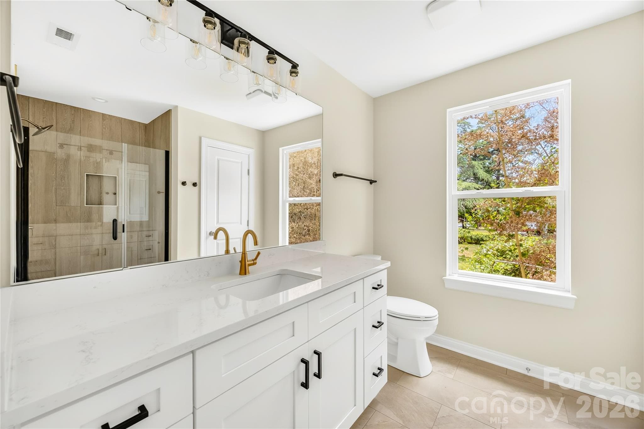 Primary bathroom with tiled walk-in shower and modern vanity in a new construction Charlotte home - 1940 Purser Drive, Charlotte