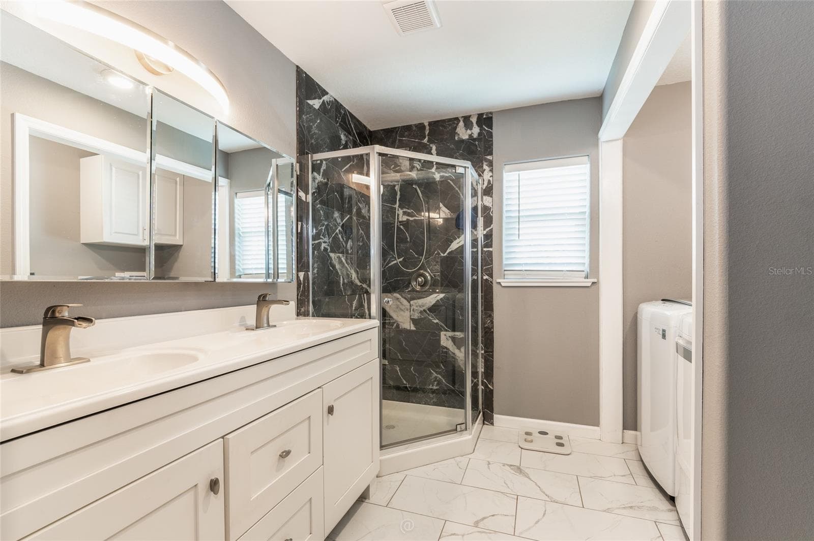 Primary bathroom with dual sinks & walk-in shower. Window to let in natural light - 904 S DAYTONA AVE, FLAGLER BEACH