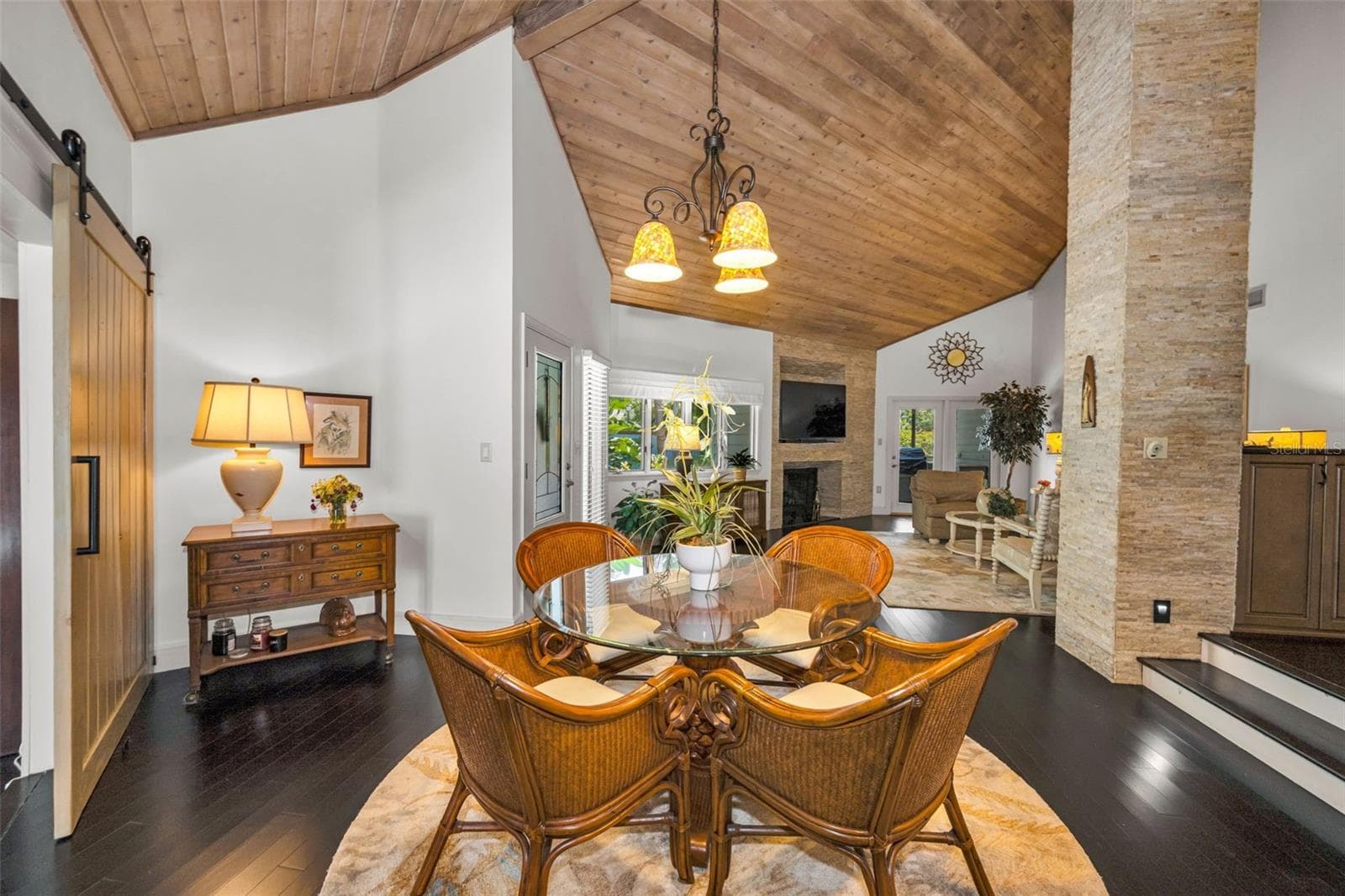 Dining room looking into the living room which opens to the screened outdoors and serene pond view. Note the incredible tongue and groove wood ceiling and stacked stone! - 10497 LONGWOOD DR, SEMINOLE