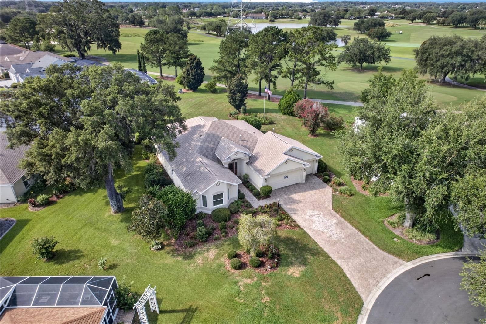 Aerial view showcasing the home’s beautiful setting, mature trees, long driveway, and nearby golf course views. - 16815 SE 85TH BELKNAP AVE, THE VILLAGES