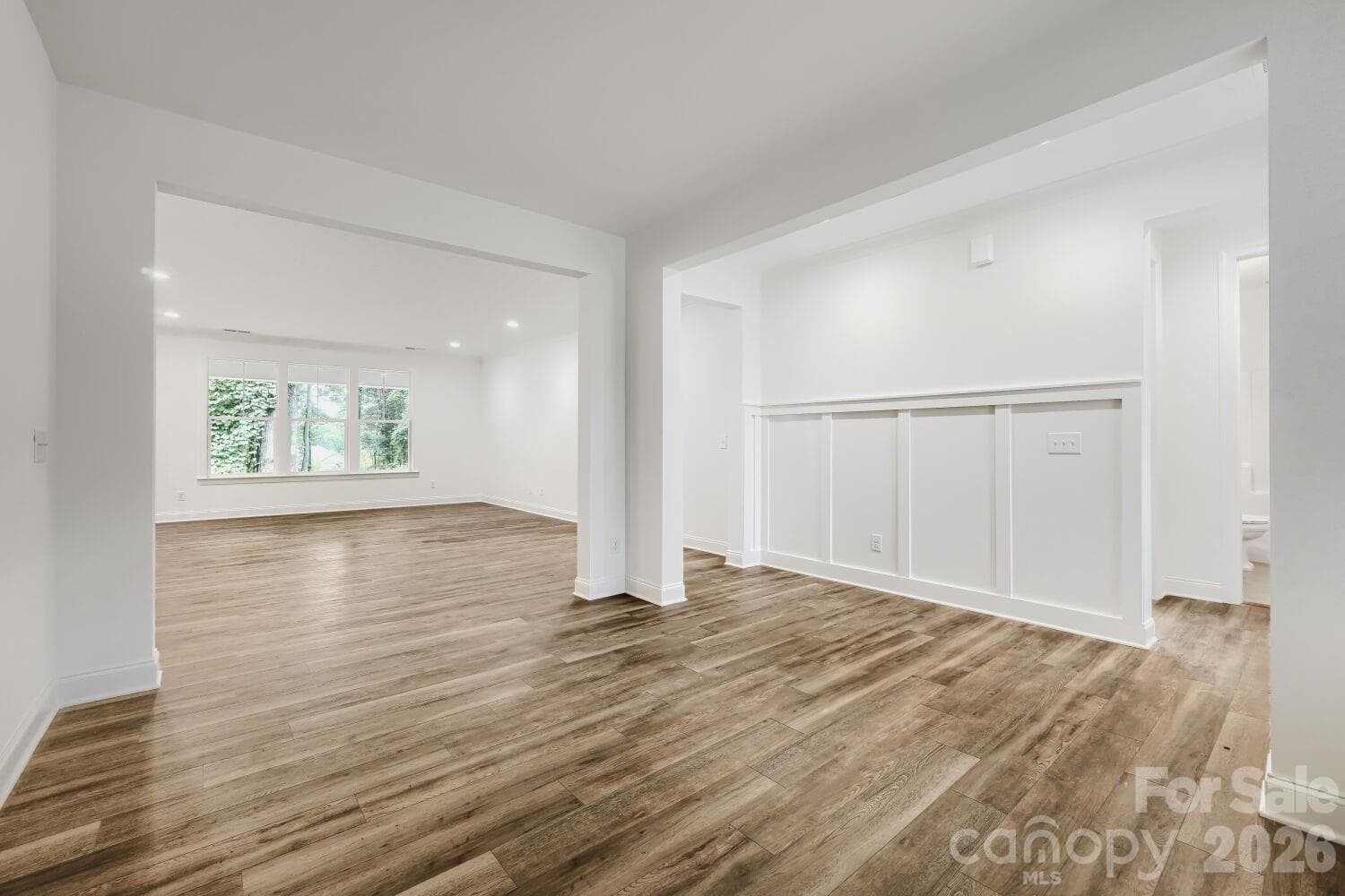 A welcoming entry flows into the open living space with warm wood-look floors and board-and-batten accent detailing. Large windows fill the room with natural light. - 2358 Fay Jones Road, Denver