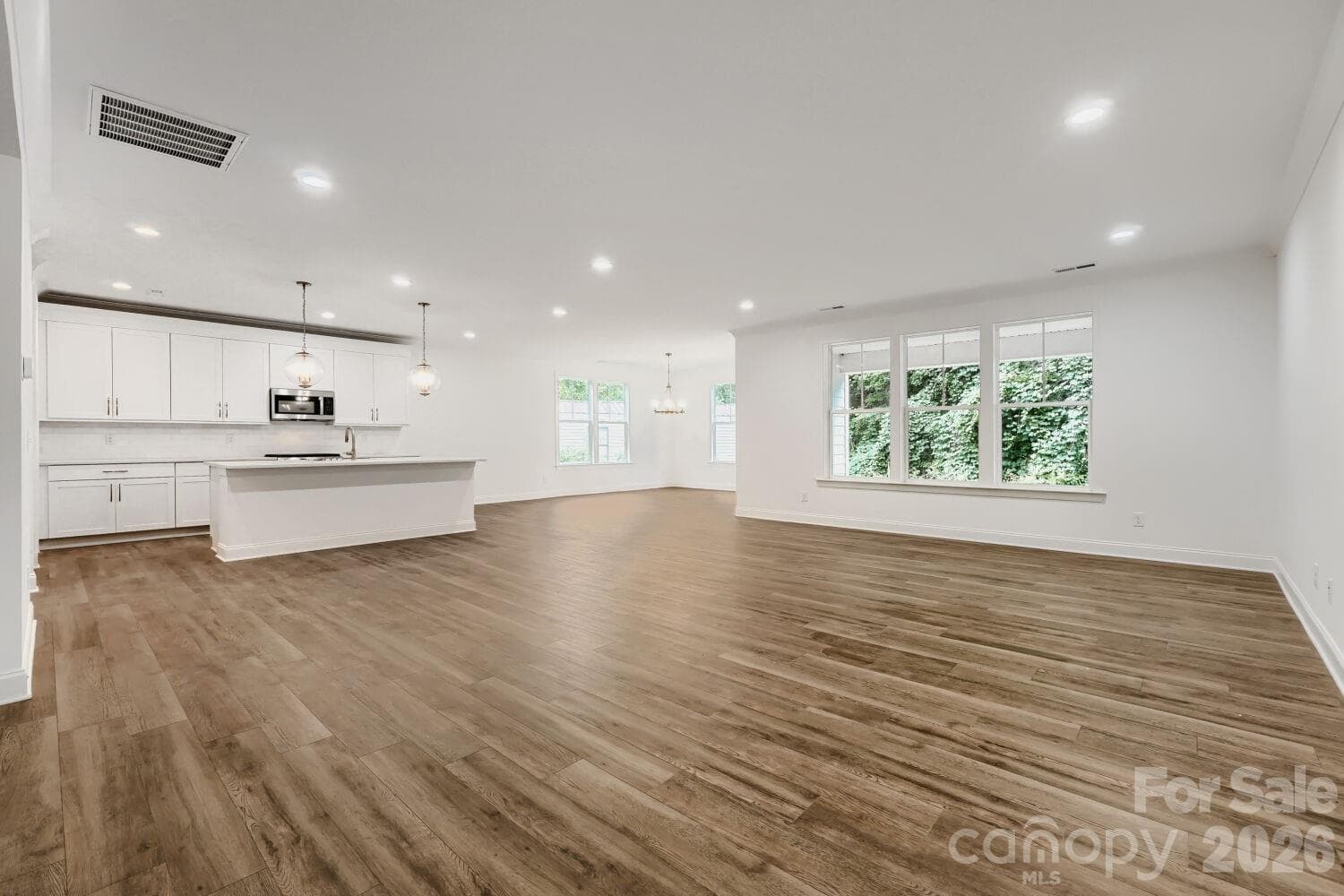 A bright, open-concept living area with rich wood-look flooring and elegant wainscoting. Wide entryways connect the space effortlessly to the rest of the home. - 2358 Fay Jones Road, Denver