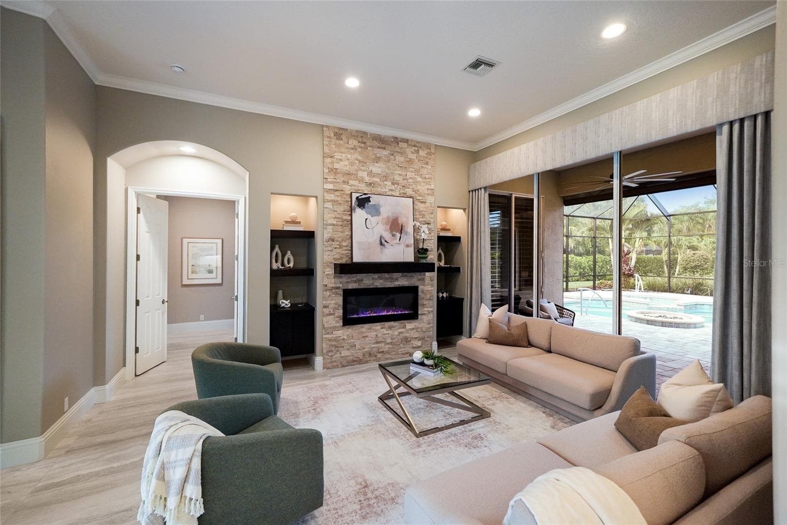 Updated living room boasting 10’ glass doors with voluminous ceilings, large porcelain tile flooring, and a fireplace stone accent wall - 8122 LONE TREE GLN, LAKEWOOD RANCH