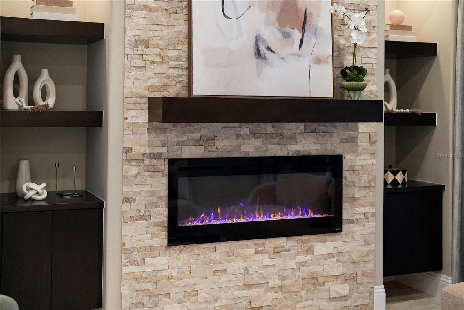 Renovated Lakewood Country Club Home with accent wall featuring electric fireplace and stone hearth - 8122 LONE TREE GLN, LAKEWOOD RANCH