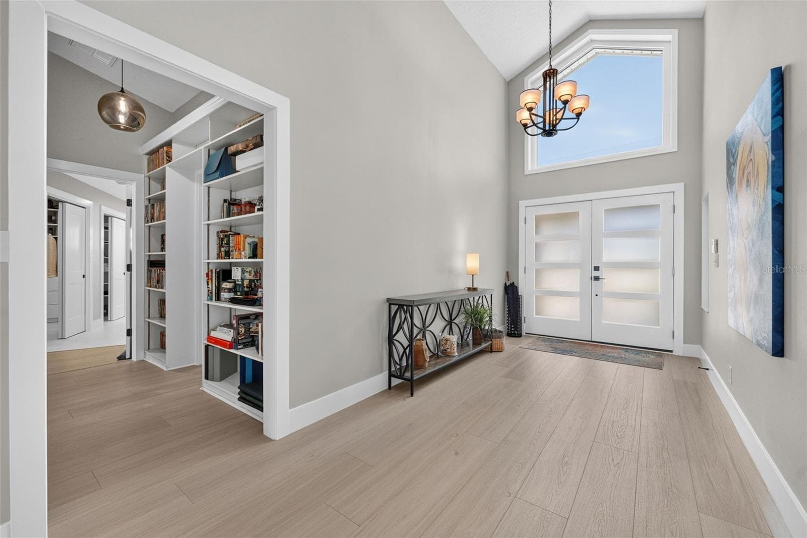 Bright and welcoming entryway featuring a large window above the double doors and a modern light fixture that enhances the natural light. - 2936 68TH AVE S, ST PETERSBURG
